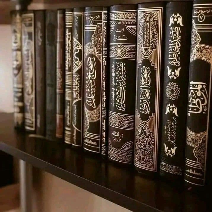 Deretan kitab bersampul gelap berhias kaligrafi emas di rak perpustakaan pesantren